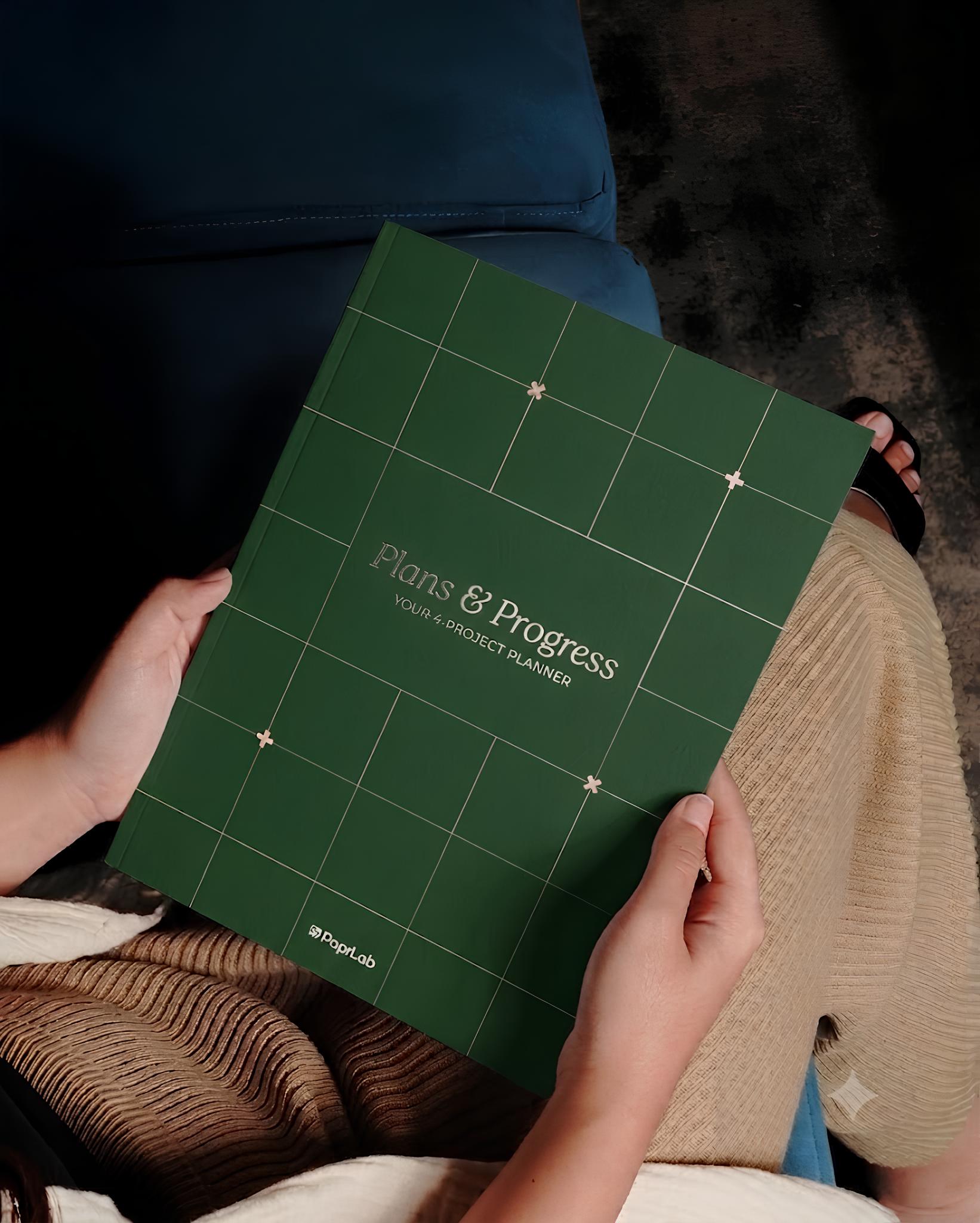 Hands holding a green Plans & Progress project planner