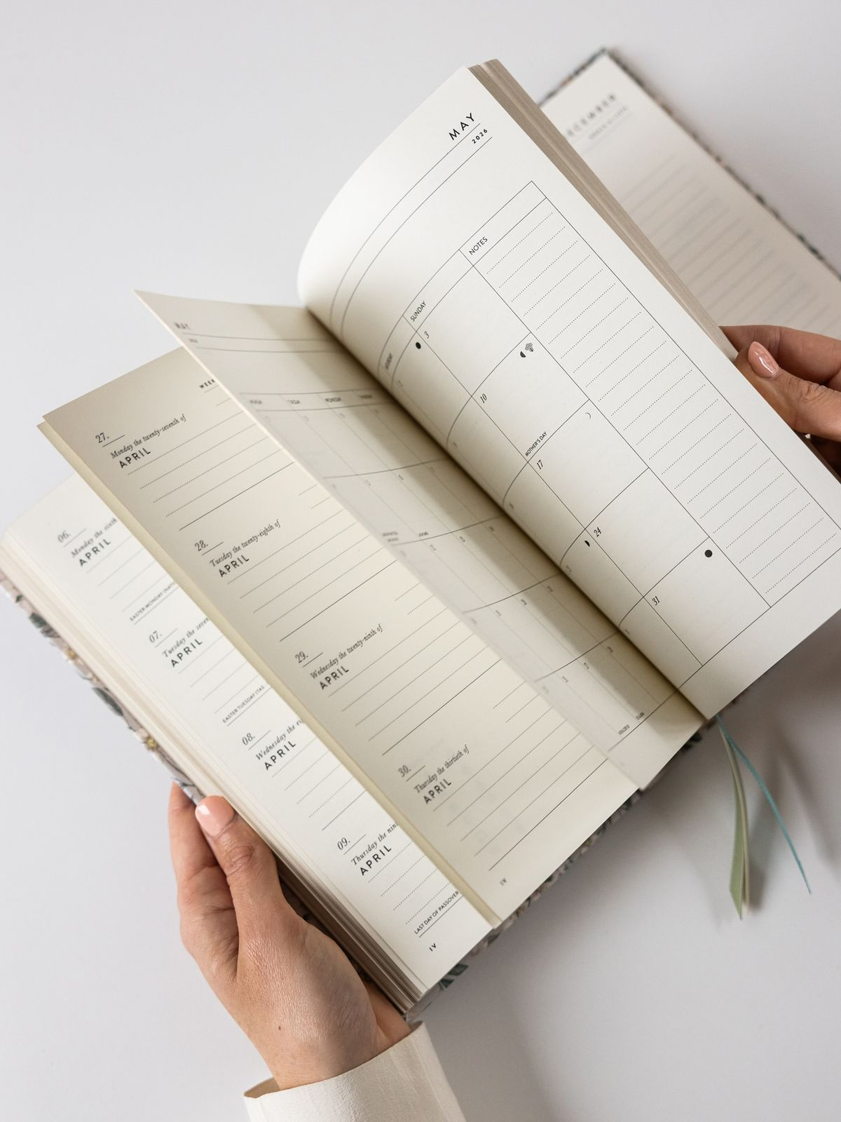 Hands flipping through the weekly and monthly pages of a PaprLab planner