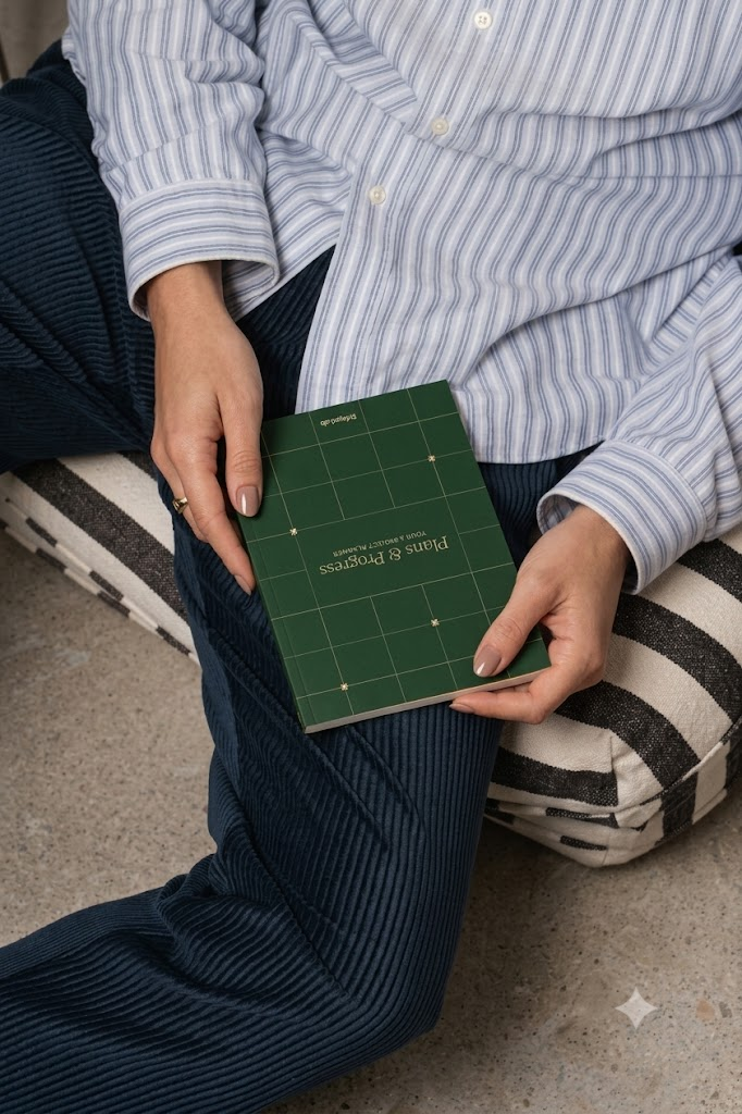 Person in a striped shirt holding a green Plans & Progress planner