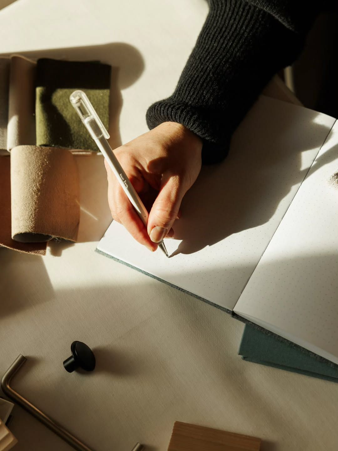 Hand writing in an open PaprLab notebook in warm afternoon light