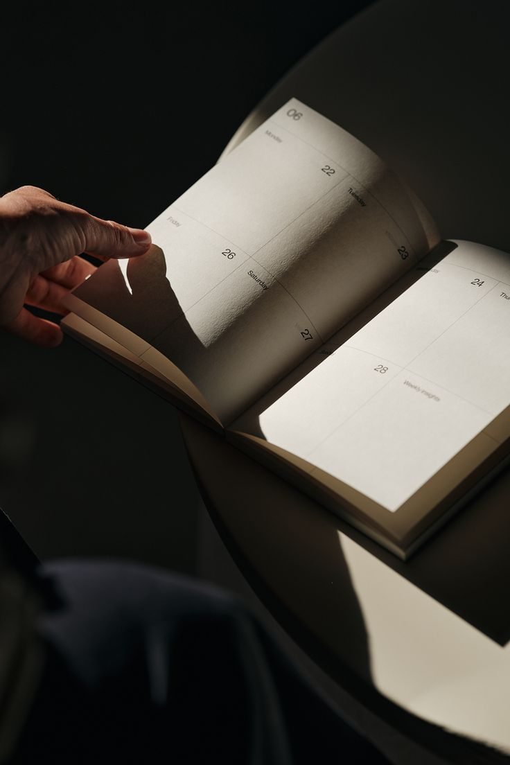 Hand turning the pages of an open weekly planner in soft sunlight